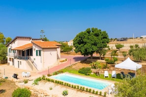 Una villa con piscina, zona de estar al aire libre y un gran árbol.