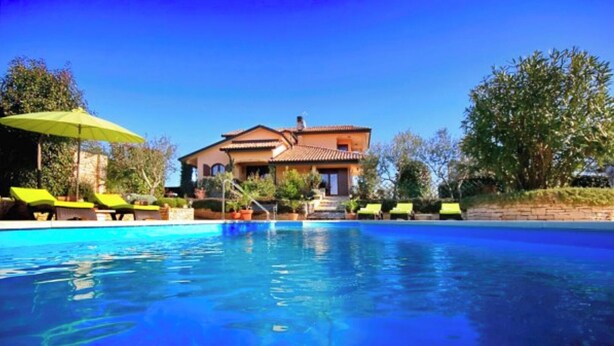 Ein Schwimmbecken mit Liegestühlen und einem Haus im Hintergrund.
