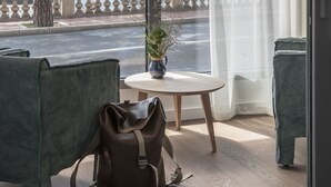 Una habitación con vista a un puerto deportivo, una mesa con un florero y dos sillas verdes.
