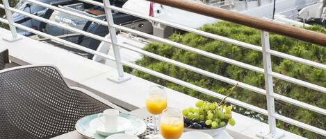 Un balcón con una mesa dispuesta para el desayuno, con vista a un puerto deportivo con yates.