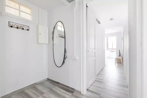 Un couloir avec une pancarte indiquant « MAISON », un miroir décoratif et un plancher en bois.