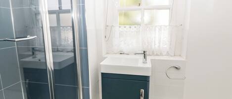 A bathroom with a glass shower enclosure, a sink with a mirror, and a toilet.