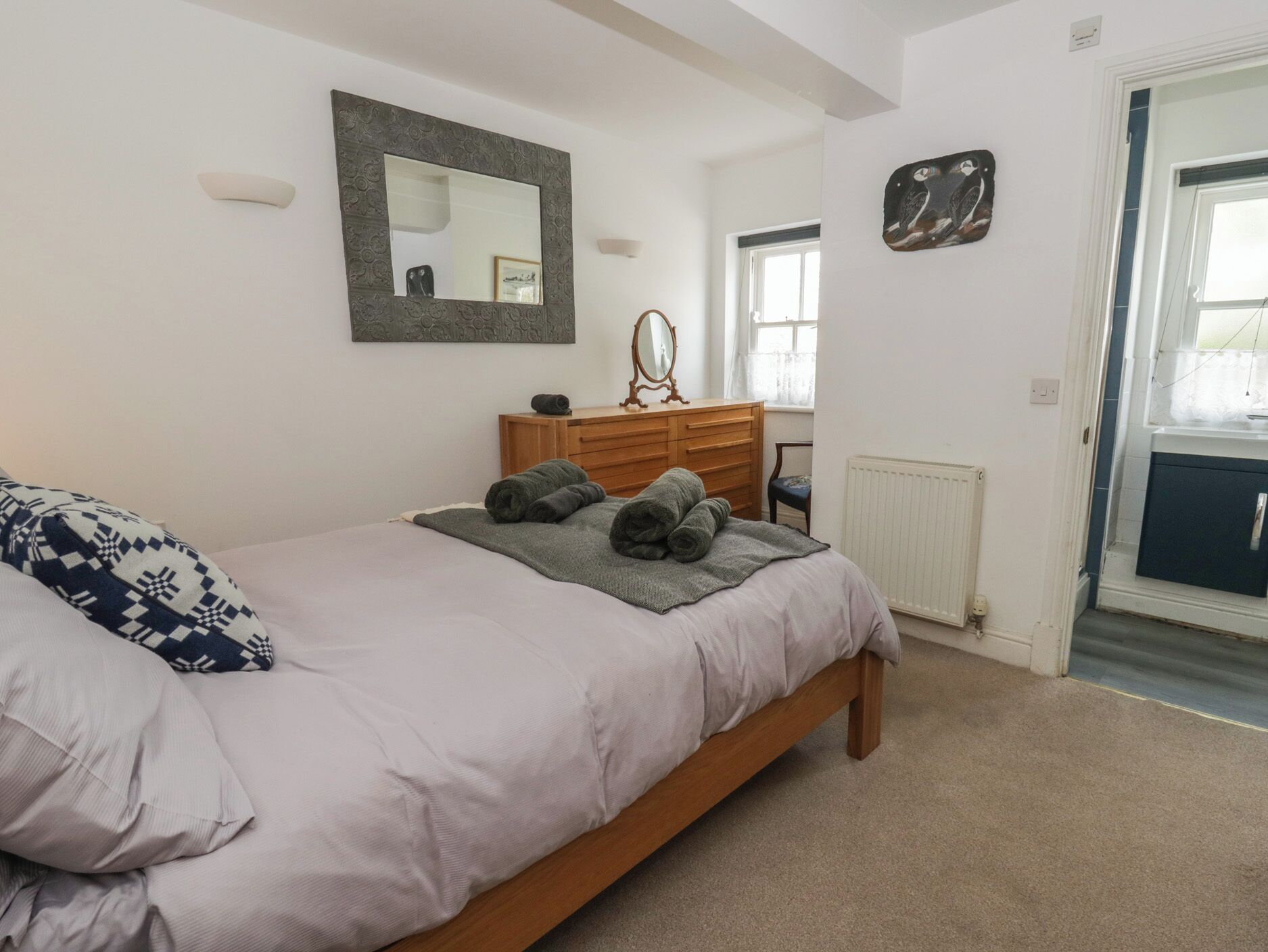A bedroom with a bed, a dresser, a mirror, and a radiator.