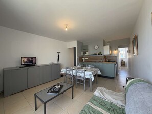 Un espace de vie compact comprenant une kitchenette, un coin repas et un téléviseur dans le salon.