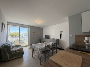 A compact living space with a dining area, kitchenette, and a sliding glass door leading to an outdoor patio.