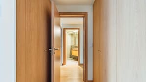 A narrow hallway with wooden doors on either side, leading to a bathroom with a mirror and sink. - Gelman's Getaway in Lisbon (Lisbon)