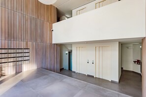 A modern hotel lobby with a wooden panel wall, a tiled floor, and a second-floor balcony. - Gelman's Getaway in Lisbon (Lisbon)