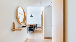 A modern interior with a wooden floor, a round mirror on a wall, a dining area with a table and chairs, and a hanging pendant light. - Gelman's Getaway in Lisbon (Lisbon)