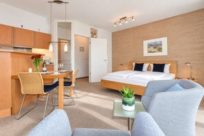 A modern hotel room with a bed, a dining area, and a kitchenette. - Ardenne House 02 - just a few meters from the fine-sand beach on the Baltic Sea (Heringsdorf (Seebad))