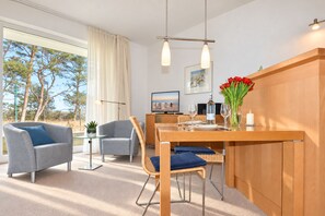 Un salon moderne avec un coin repas, comprenant une grande fenêtre, un téléviseur à écran plat et une table à manger en bois.