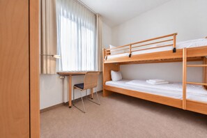 A single-bedded room with a desk and chair, a window with curtains, and a radiator. - House Ardenne 01 - only a few meters to the fine sandy Baltic Sea beach (Heringsdorf (Seebad))