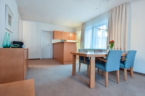 A modern hotel room with a dining area, a kitchenette, and a large window with curtains. - House Ardenne 01 - only a few meters to the fine sandy Baltic Sea beach (Heringsdorf (Seebad))