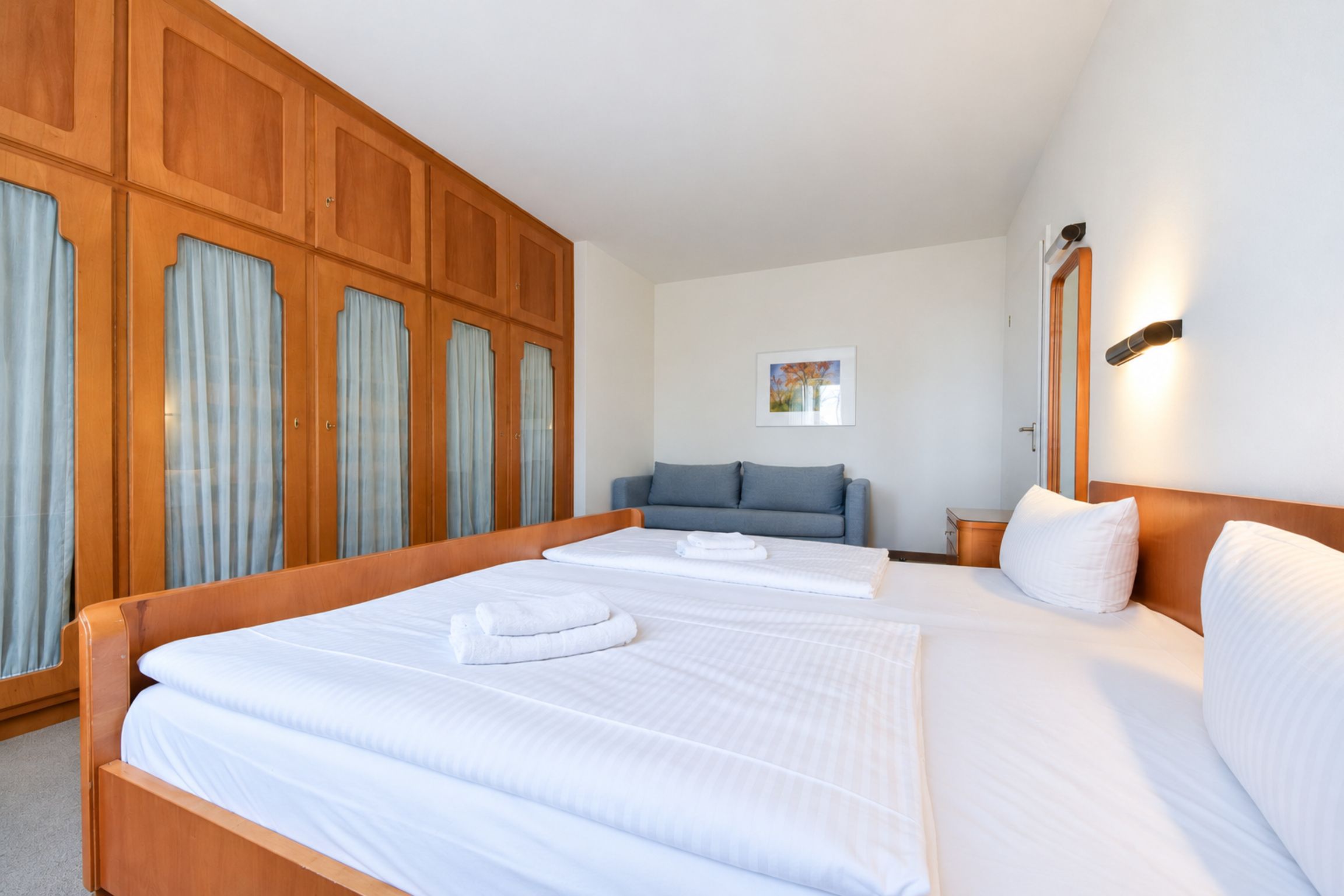 Een hotelkamer met een groot bed, een bank en een kledingkast.