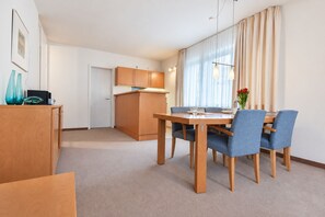A modern, well-lit room with a dining table, chairs, and a kitchen area. - House Ardenne 01 - only a few meters to the fine sandy Baltic Sea beach (Heringsdorf (Seebad))
