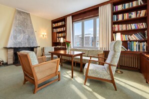 A cozy living room with a fireplace, a bookshelf, and a view of the city through large windows. - House Ardenne 04 - only a few meters to the fine sandy Baltic Sea beach (Heringsdorf (Seebad))