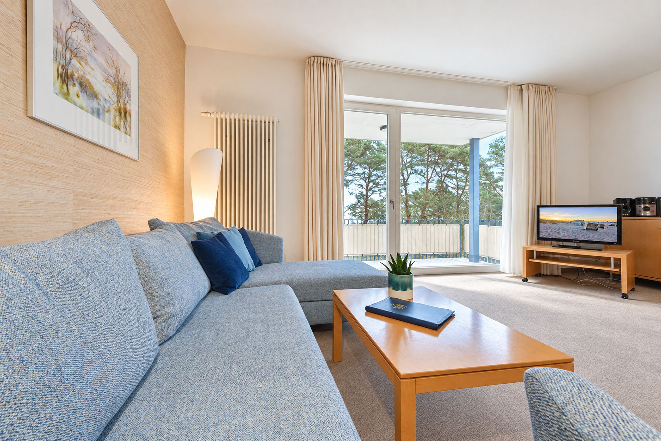 A modern living room with a sofa, coffee table, and a flat-screen TV on a stand.