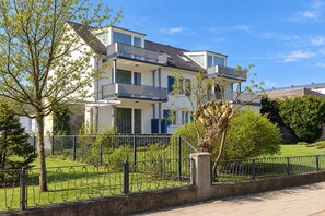 A multi-story residential building with balconies, a fenced yard, and mature trees. - House Ardenne 04 - only a few meters to the fine sandy Baltic Sea beach (Heringsdorf (Seebad))