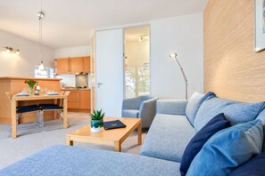 A modern living space with a sofa, coffee table, and dining area. - House Ardenne 04 - only a few meters to the fine sandy Baltic Sea beach (Heringsdorf (Seebad))