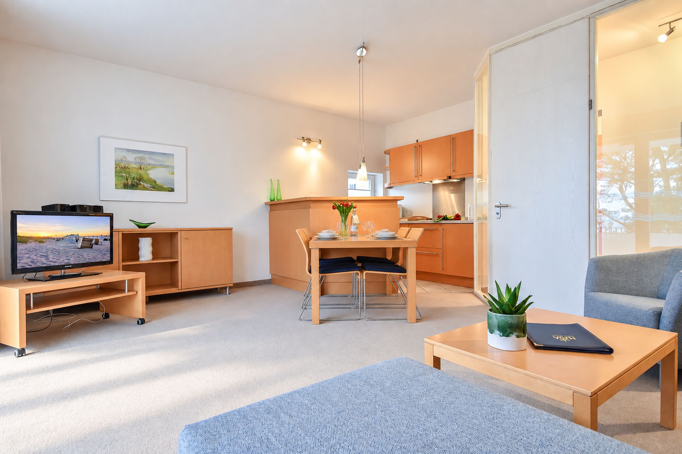A compact living space with a television, a dining area, a kitchen, and a seating area.