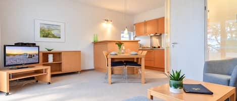A compact living space with a television, a dining area, a kitchen, and a seating area.
