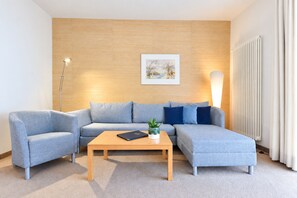 Un salon moderne avec un canapé d’angle, une table basse et un lampadaire.
