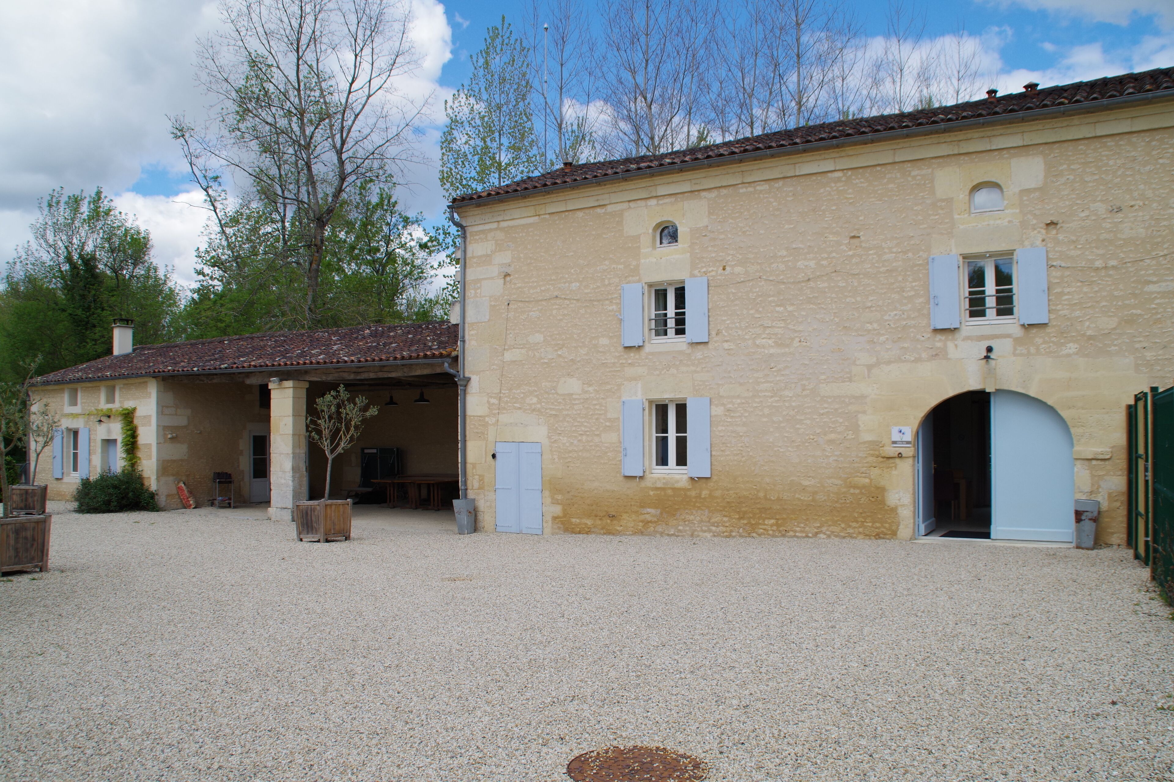 A building with a gravel courtyard, a covered porch, and a door with a small window.