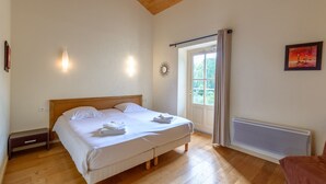 Un dormitorio con una cama de madera, una mesita de noche, un radiador y una ventana con cortinas.