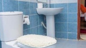 A bathroom with a toilet, a sink, and a mirror.