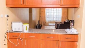 A kitchen with wooden cabinets, a countertop, a toaster, a kettle, and a coffee maker.