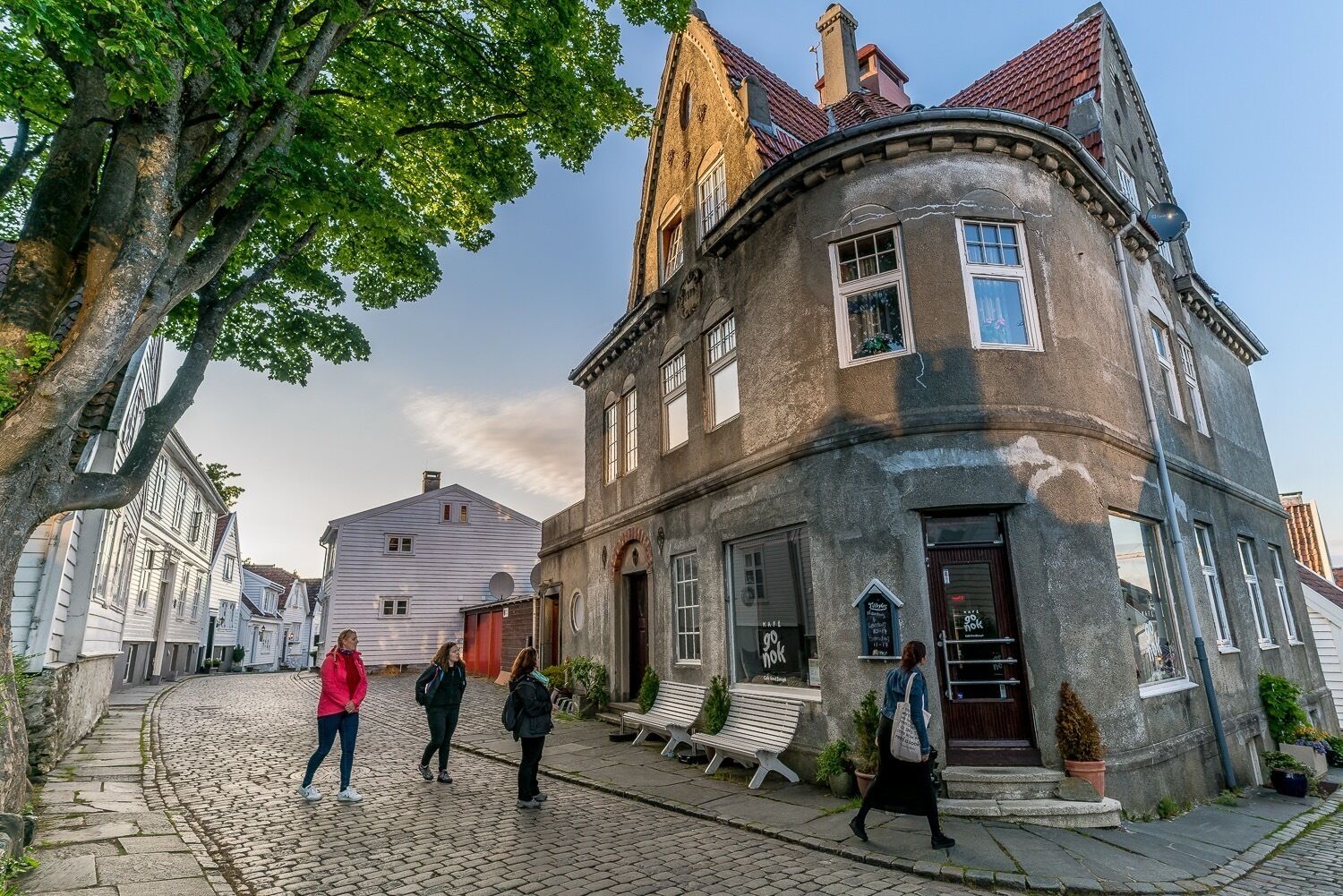 Una calle adoquinada con edificios históricos, bancos y algunos peatones.