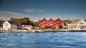 A waterfront property with a red building, white buildings, and a dock extending into the water.