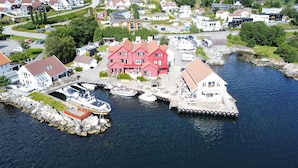 A waterfront property with a dock, boats, and a large red building.