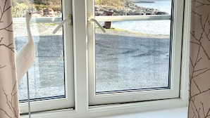 A window with a view of a rocky shoreline and a body of water.