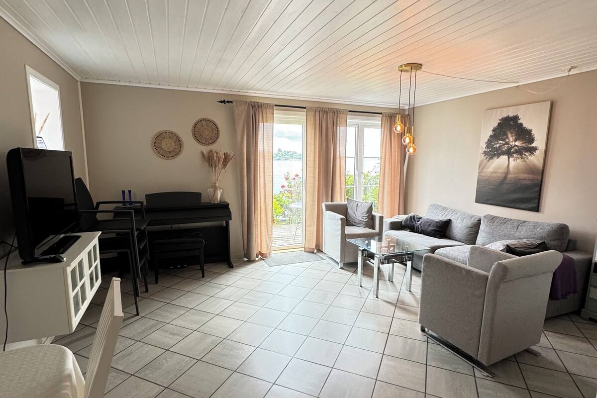 A spacious living room with a piano, a sofa, and a dining table.