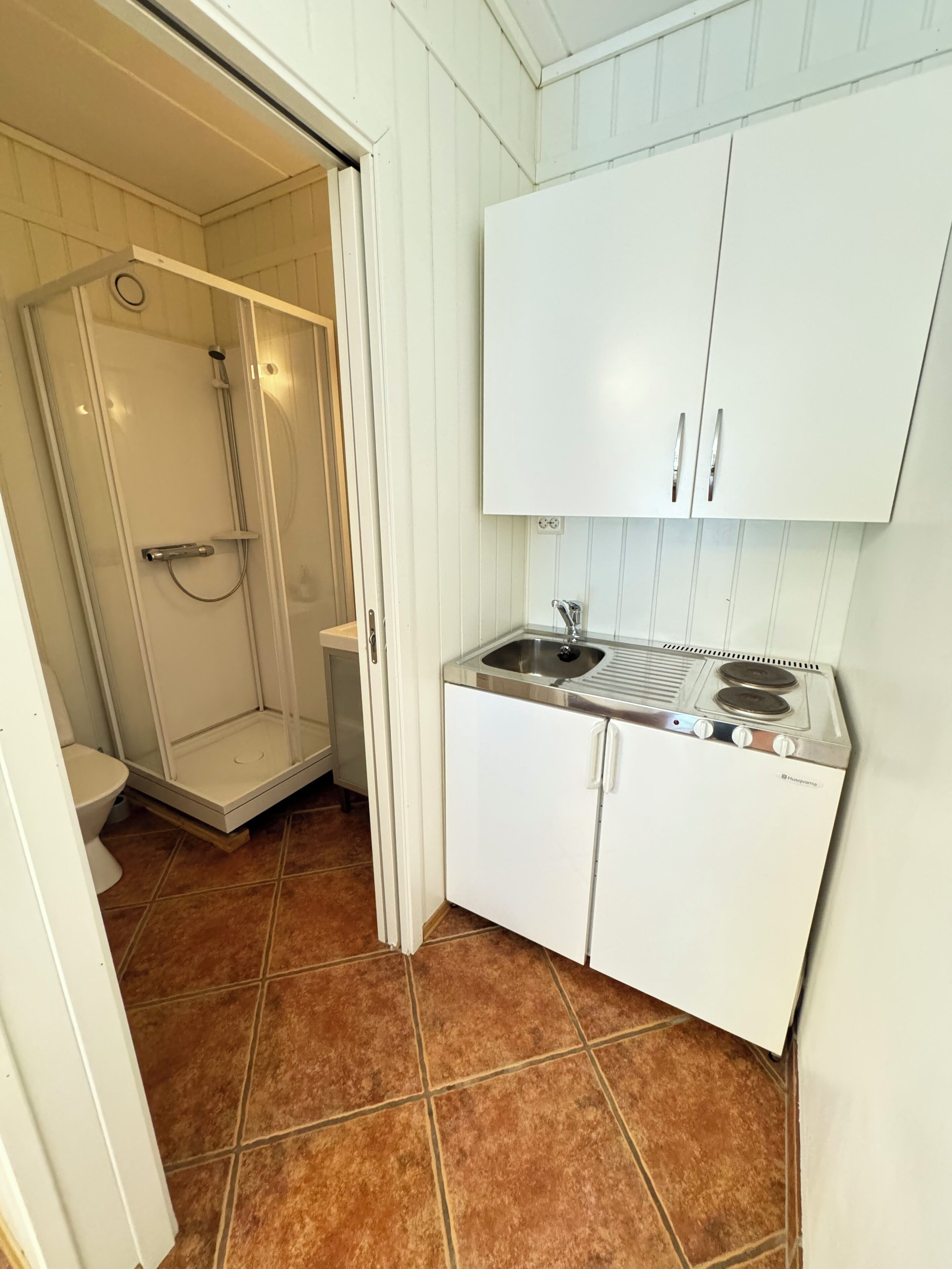 A compact kitchen with a built-in stove, a sink, and white cabinets.