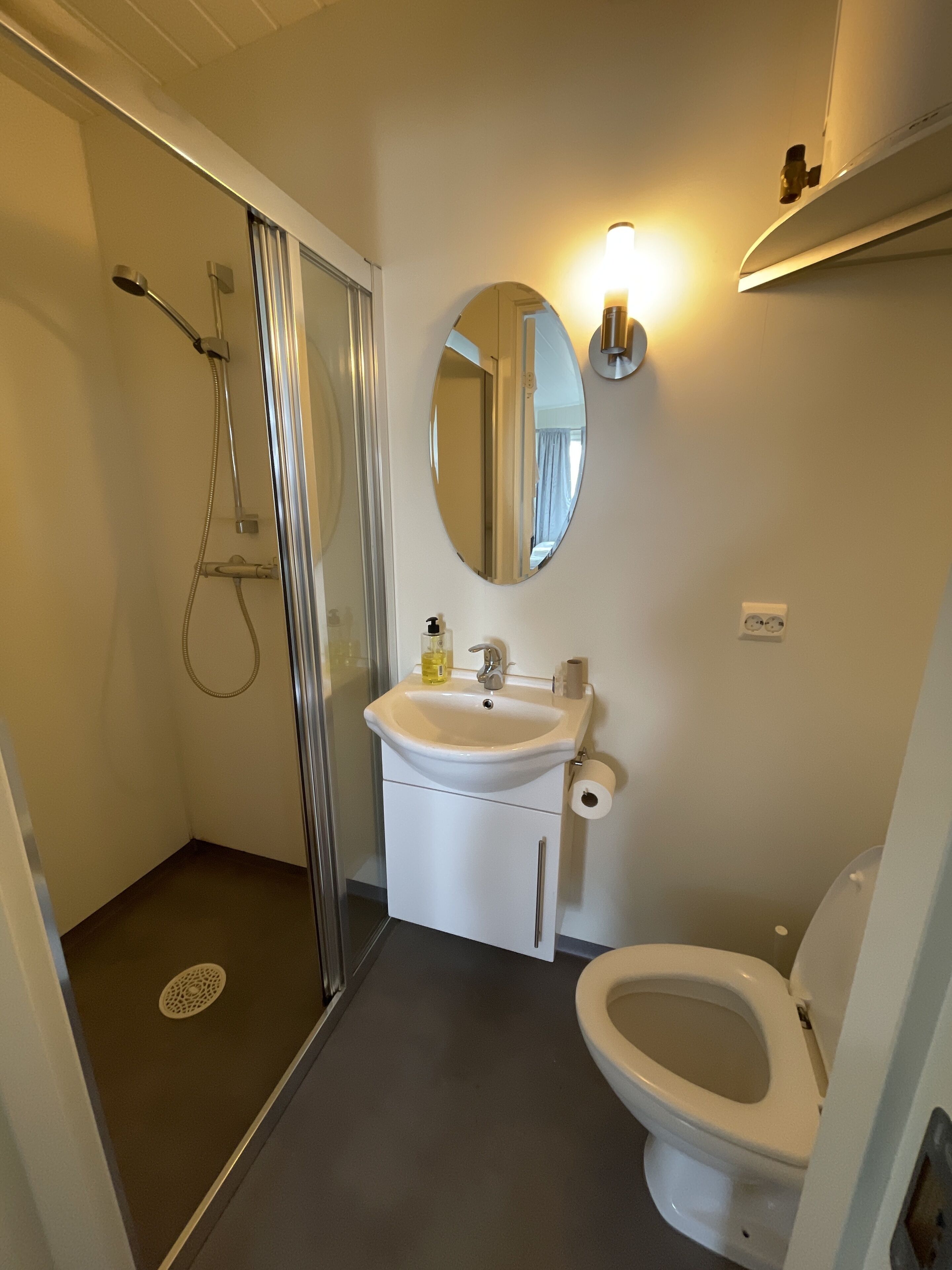 A bathroom with a shower, sink, toilet, and a mirror.