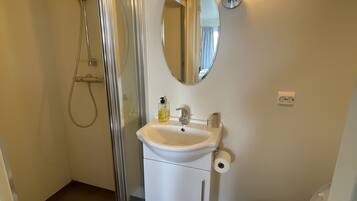A bathroom with a shower, sink, toilet, and a mirror.