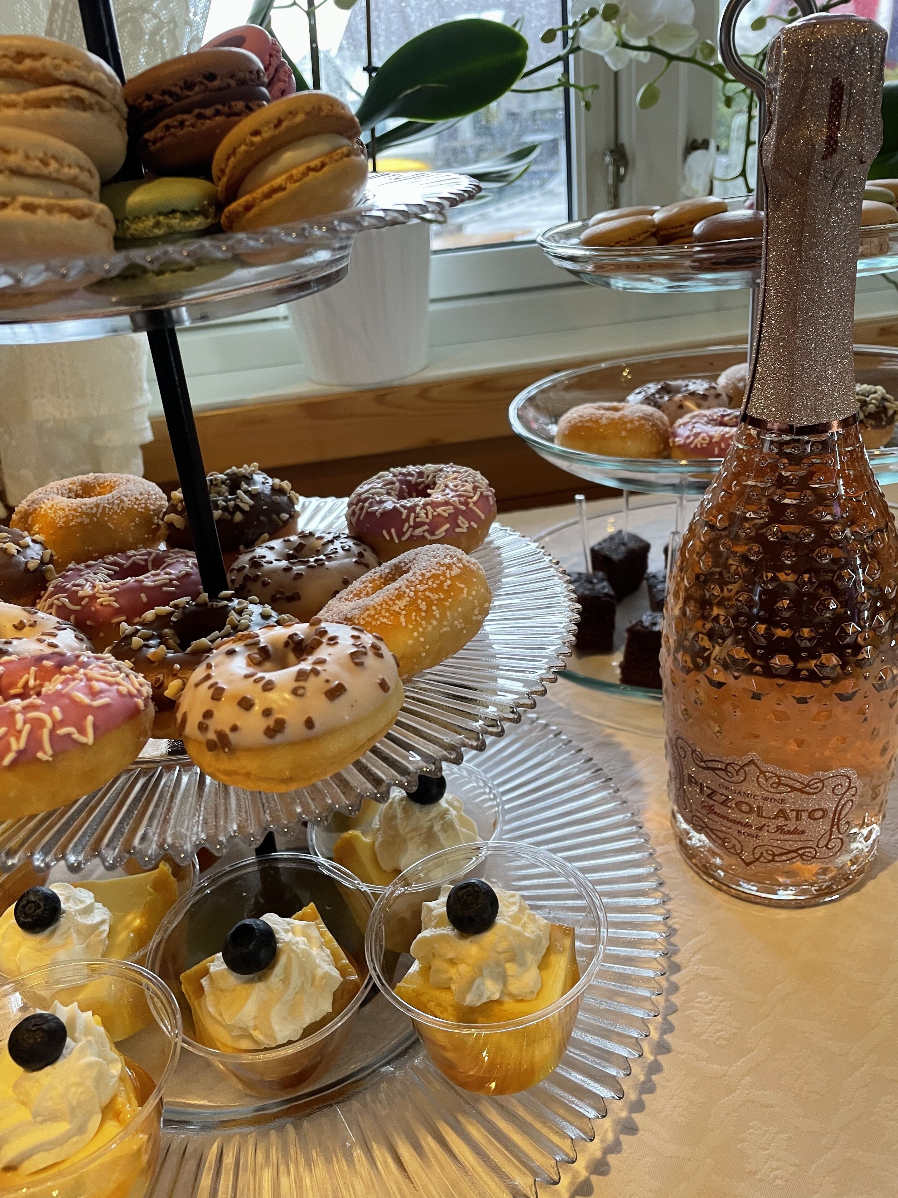A dessert display with macarons, donuts, and small dessert cups.