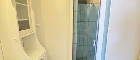 Un baño con inodoro, lavamanos y zona de ducha.