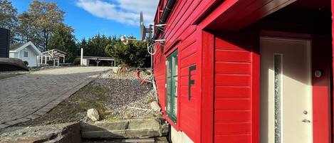 A red building with a wooden deck, a satellite dish, and a door marked with an 'F'.