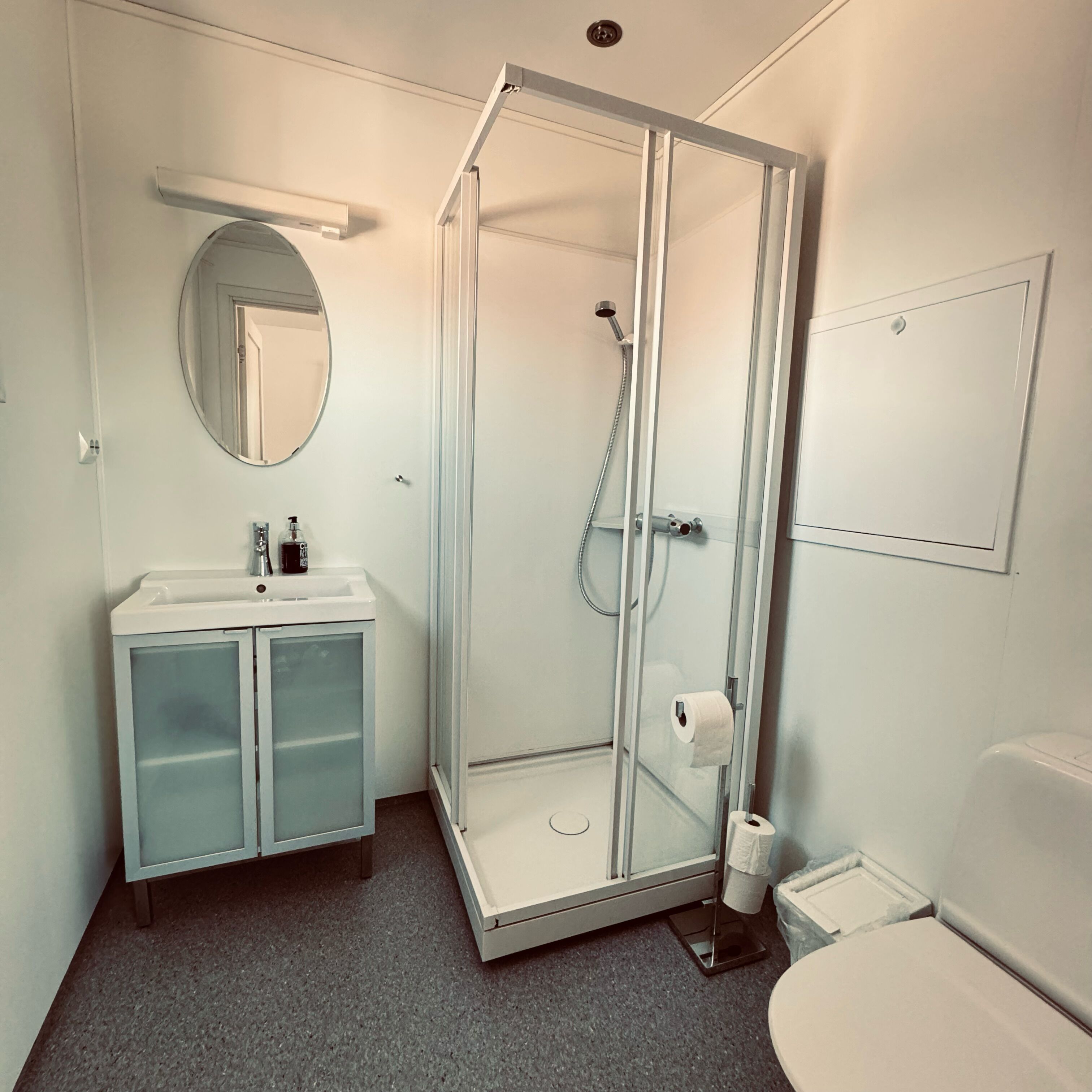 Un baño moderno con ducha de vidrio, lavabo con espejo e inodoro.