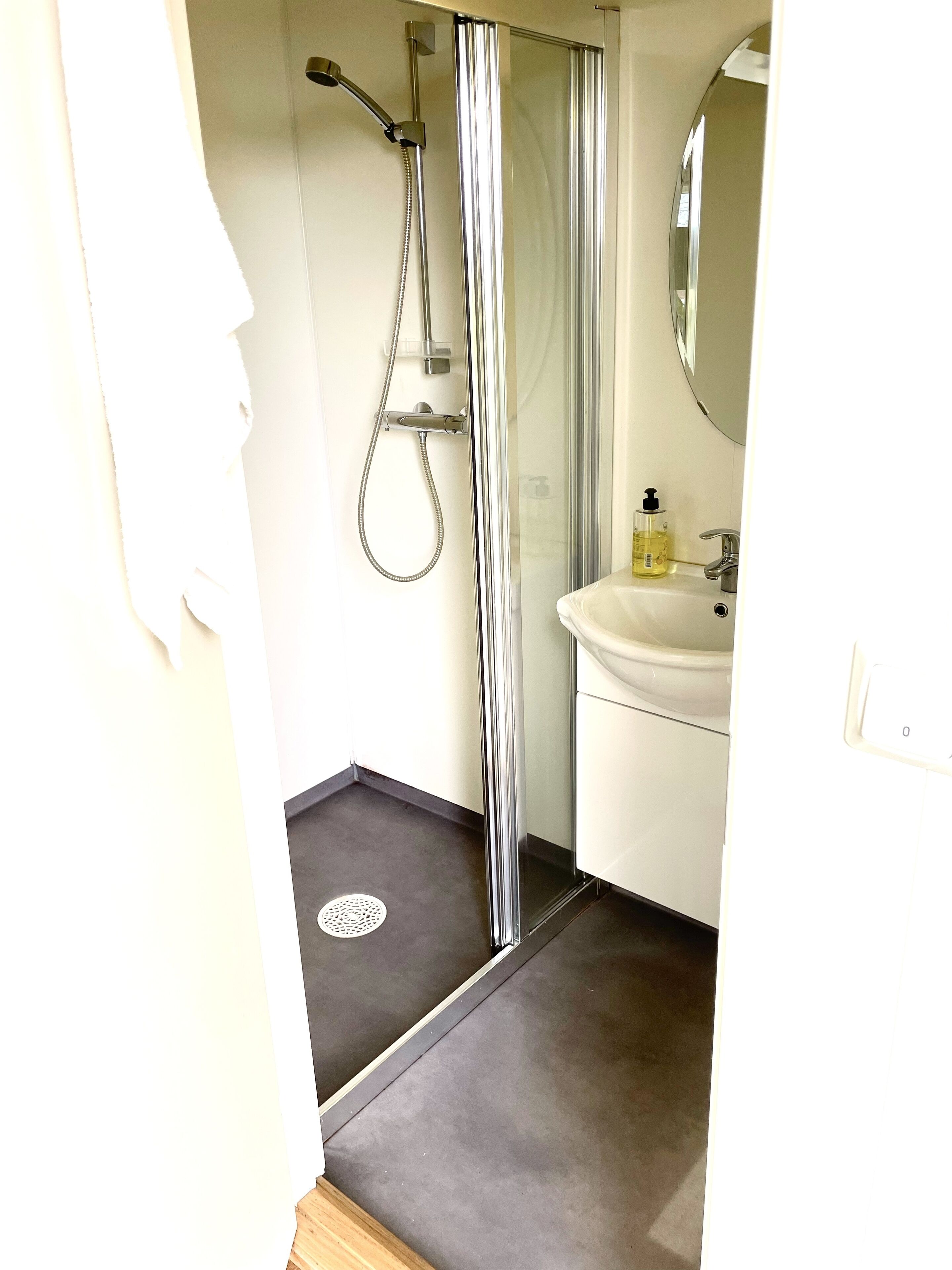 A bathroom with a shower, a sink, and a mirror.