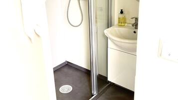 A bathroom with a shower, a sink, and a mirror.