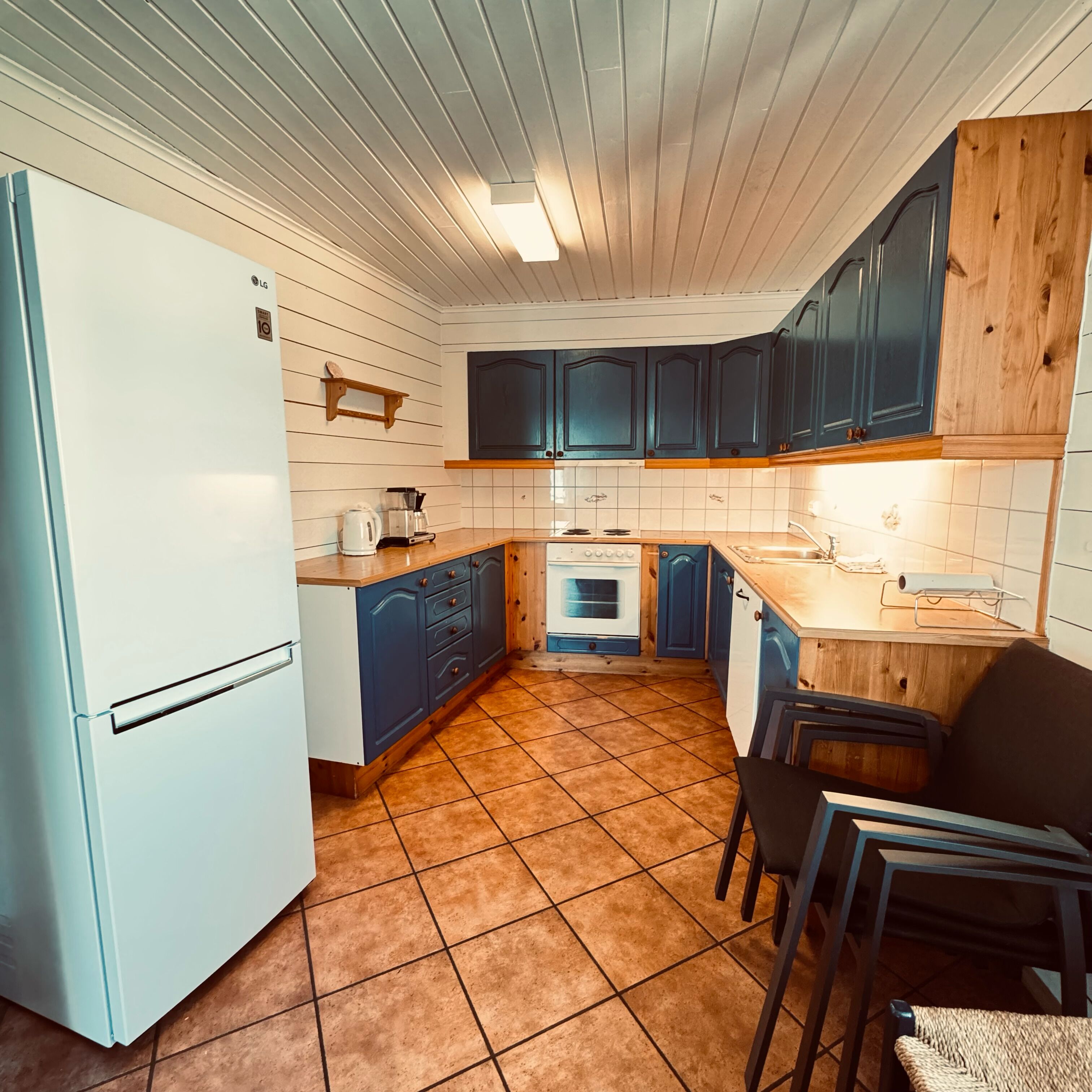 A kitchen with white cabinets, a white refrigerator, a stove, and a sink.
