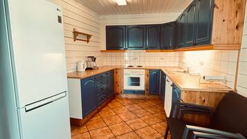 A kitchen with white cabinets, a white refrigerator, a stove, and a sink.