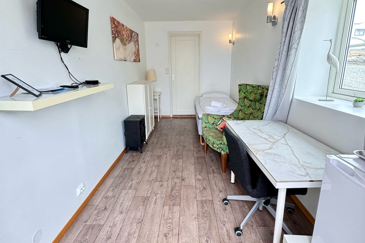 A compact room with a bed, a desk, a TV, and a small cabinet.