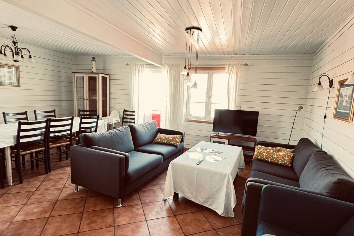 A cozy living room with a dining area, a TV, and a window with curtains.