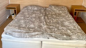 Un lit avec un matelas à motifs, une tête de lit en bois et deux tables de chevet dotées d’étagères.