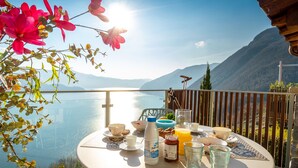 A table set for breakfast with a scenic lake view, a wooden fence, and mountains in the background. - EnjoyIseoLake - Colosseum - Parzanica (Parzanica)