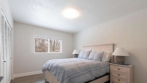 Ein Schlafzimmer mit Bett, Nachttischen und einem Fenster.